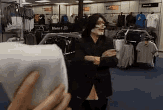 a man with a face mask is standing in a clothing store .