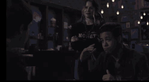 a man and a woman are sitting at a table in a dark room in a restaurant .