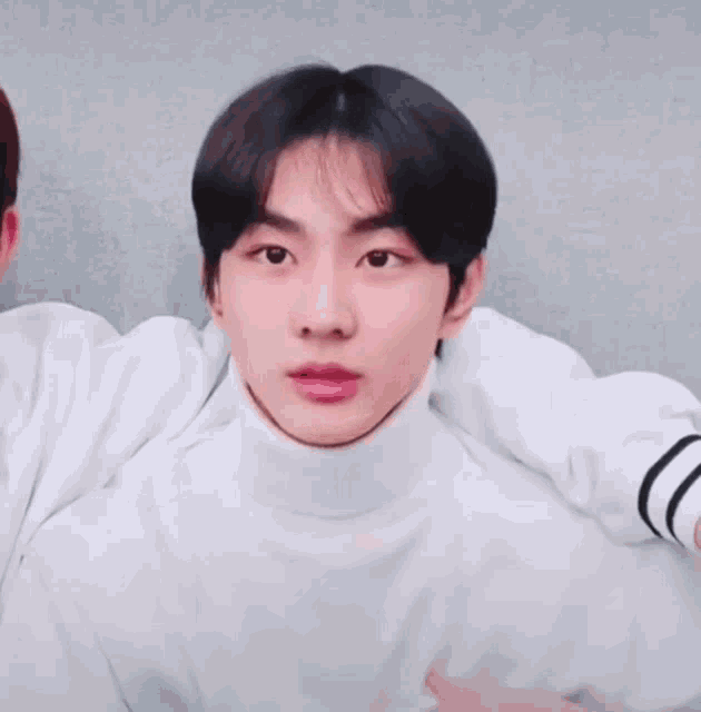 a man wearing a white turtleneck sweater smiles for the camera
