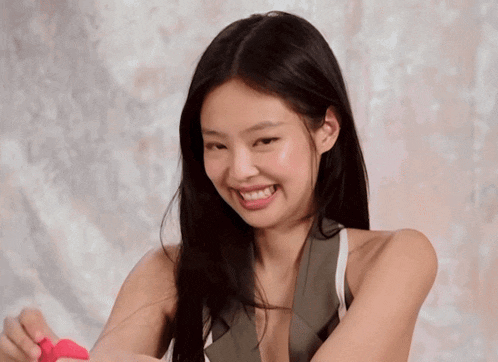 a woman is smiling while holding a pink object