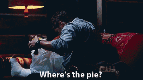 a man sits on a couch looking at a woman 's leg with the words " where 's the pie " above him