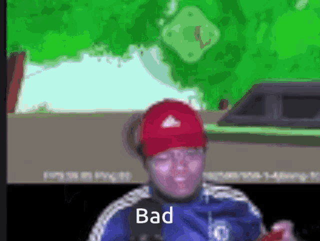 a man wearing a red hat and a blue jacket is holding a cell phone and says bad .