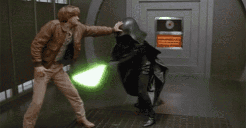 a man in a brown jacket is standing next to a man in a black suit holding a green lightsaber .