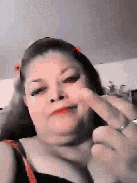 a woman is making a funny face with her finger in her nose