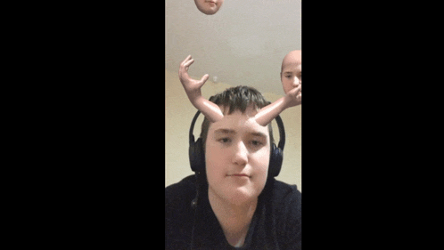 a young man wearing headphones has a doll 's head on his head