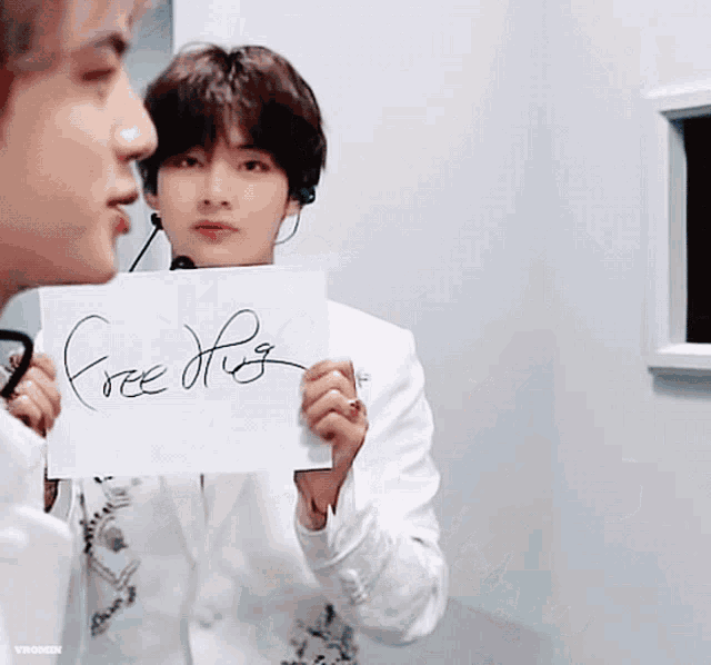 a man in a white suit holds a sign that says free hug