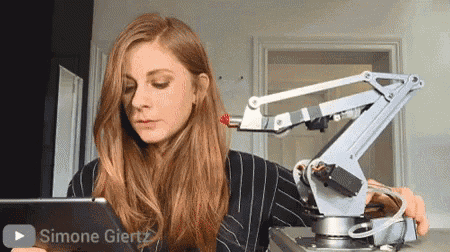 a woman is using a tablet next to a robotic arm with the name simone giertz on the bottom