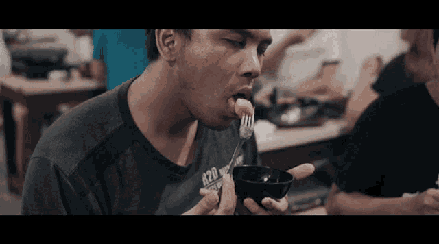 a man wearing a shirt that says a20 is eating food