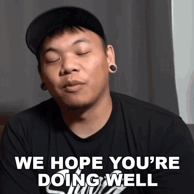 a man wearing a hat and ear plugs says we hope you 're doing well