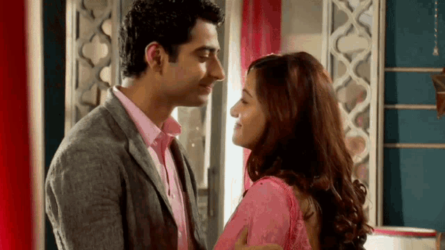 a man in a suit and a woman in a pink dress are kissing