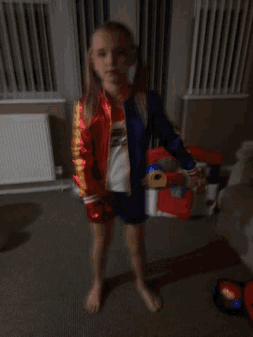 a little girl wearing a superhero costume is standing on the floor
