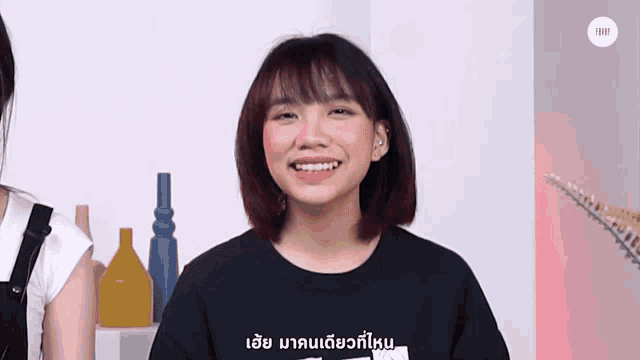 a woman wearing a black shirt with foreign writing on it smiles