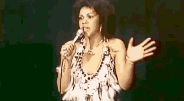 a woman in a white dress is dancing on a stage in front of a microphone .
