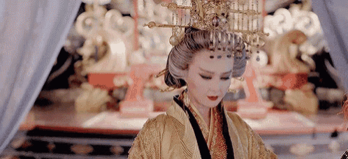 a woman in a traditional costume with a crown on her head is sitting in a room .