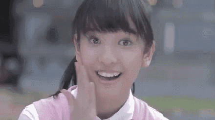 a young girl in a pink shirt and white shirt is smiling and waving .