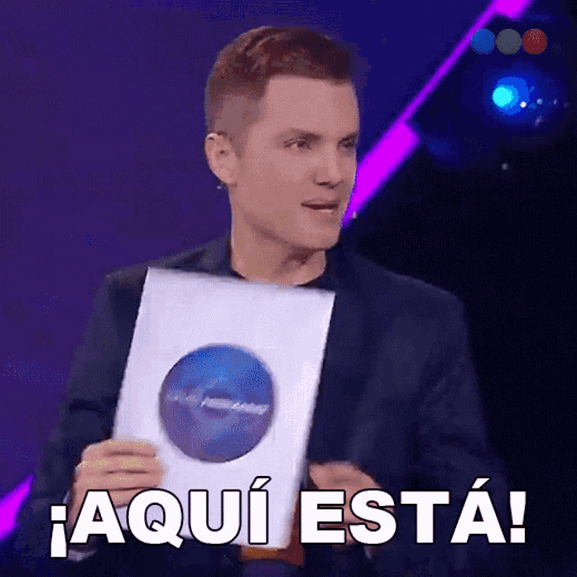 a man in a suit holds a piece of paper that says " aqui esta "