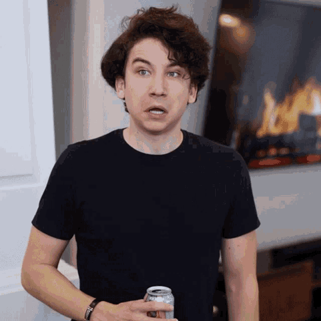 a man in a black shirt is holding a can of beer
