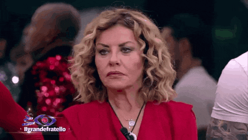 a woman in a red dress is sitting in front of a sign that says grande fratello