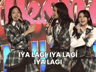 a group of girls are singing into microphones while standing next to each other on a stage .