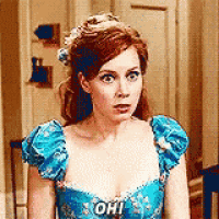 a woman in a blue dress is standing in front of a door and making a funny face .