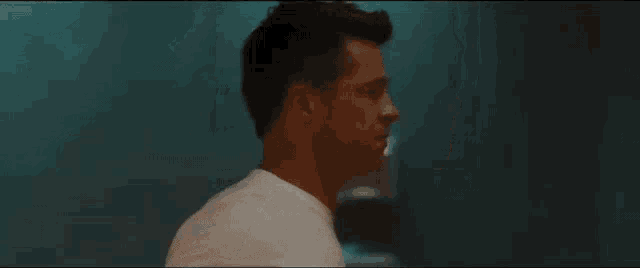 a man in a white shirt is standing in a dark room with his hands outstretched .