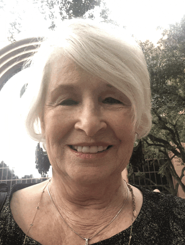 a woman wearing a necklace and earrings smiles at the camera
