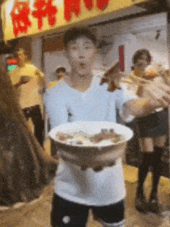 a man is holding a bowl of food in front of a sign that says ' a ' on it