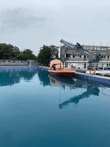 a boat is floating in a swimming pool with a crane nearby