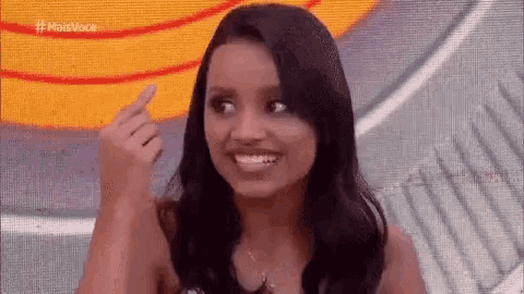 a woman is smiling and giving the middle finger while sitting on a stage .