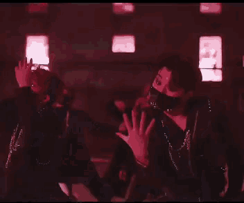 a group of people are dancing in a dark room with red lights .