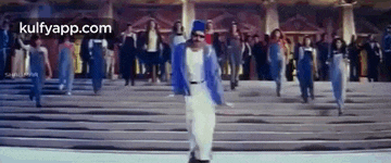 a man in a blue jacket is walking down a set of stairs with a crowd of people behind him .