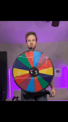 a man with a beard is holding a colorful wheel of fortune in front of him