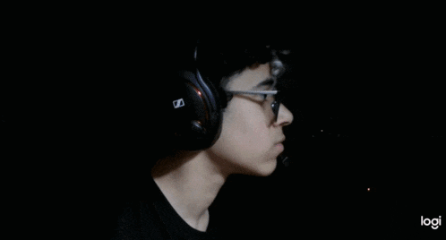 a young man wearing glasses and headphones looks at a computer screen .
