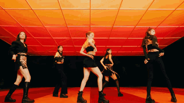 a group of women are dancing in a room with red lights