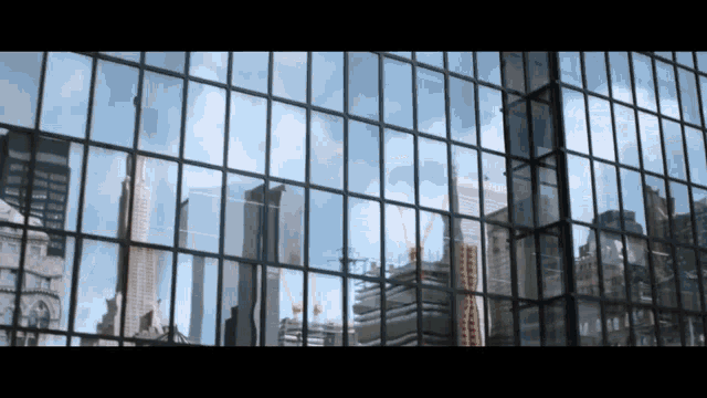 a city skyline is reflected in the windows of a large building