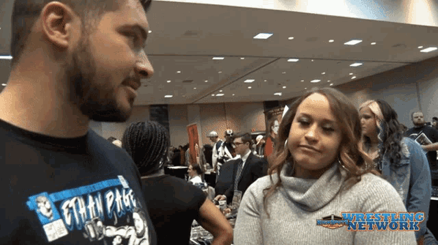 a man wearing a t-shirt that says ethan pace talks to a woman
