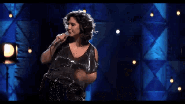 a woman singing into a microphone on stage