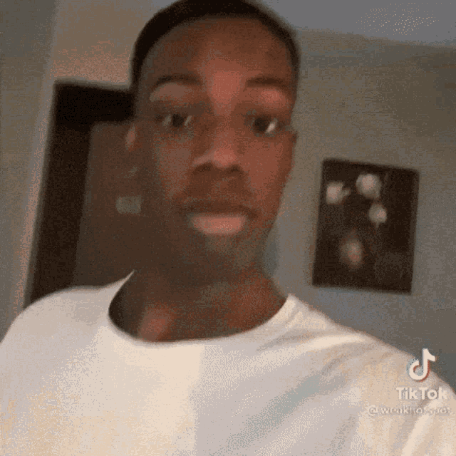 a man in a white shirt is making a funny face while looking at the camera .