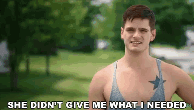 a shirtless man with a star tattoo on his chest is standing in a park .