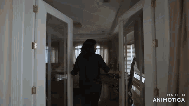 a woman in a black shirt is walking through a doorway in a living room .