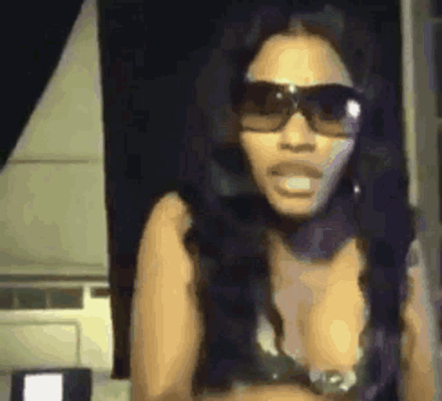 a woman wearing sunglasses and a bra is standing in a dark room