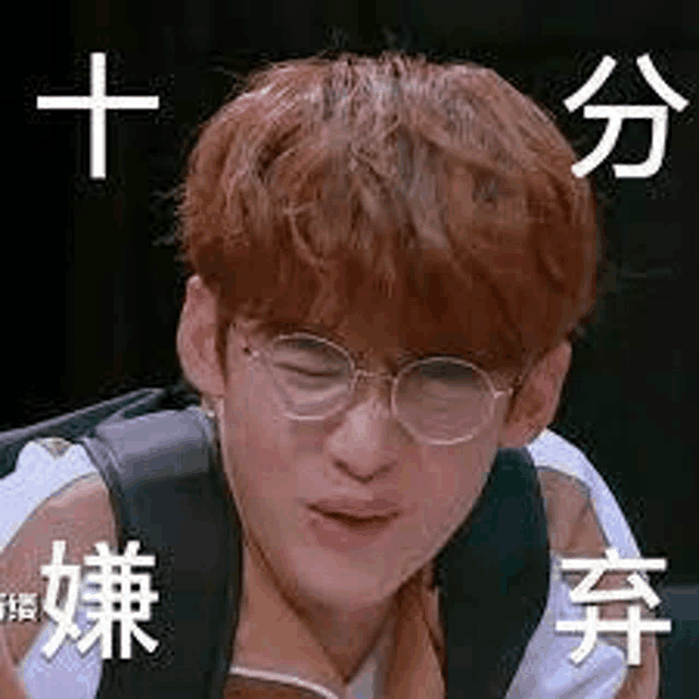 a young man wearing glasses and a backpack making a funny face .