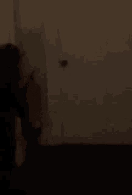 a person is laying on a bed in a dark room with a white wall behind them .