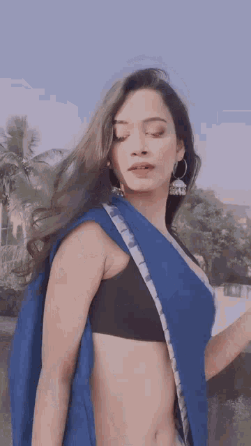 a woman is wearing a blue saree and black bra