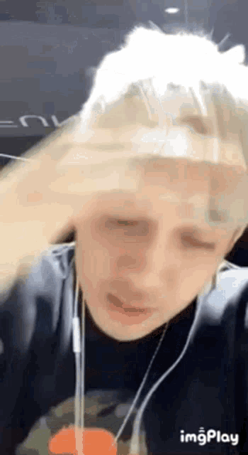 a man is wearing headphones and holding his head in pain .