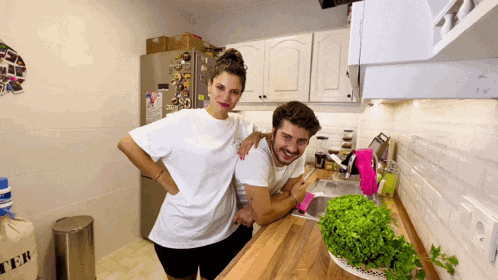 a man and woman in a kitchen with a trash can that says " ter "
