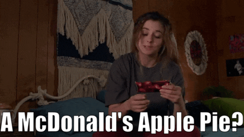 a woman is laying on a bed with a mcdonald 's apple pie in the background