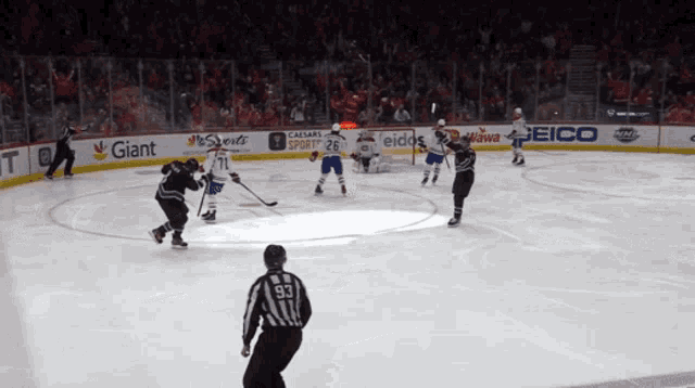 a hockey game is being played in a stadium with giant and geico ads on the ice
