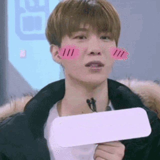 a young man is holding a piece of paper in front of his face and making a funny face .
