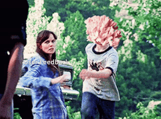 a woman in a blue shirt is standing next to a boy in a white shirt with a paw on it